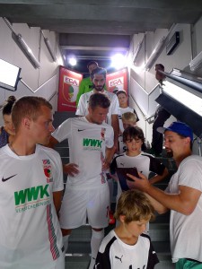 Regisseur Wolf Ehrhardt gibt neuen Text vor. Marinus mit Daniel Baier und Halil Altintop (beide FC Augsburg). beim Sky-Dreh in der WWK-Arena Augsburg, Sommer 2015